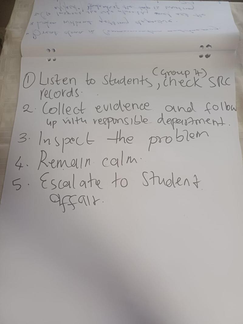 Flipchart from group 4 listing five steps: listen to students and check SRC records, collect evidence and follow up with the responsible department, inspect the problem, remain calm, escalate to Student Affairs