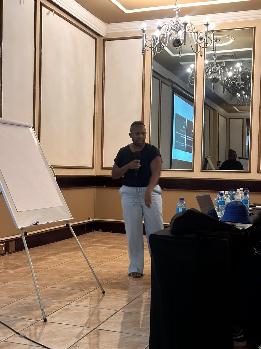 Facilitator speaking with a microphone beside a flipchart